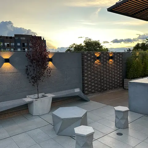 Terraza social de 5924 LOFT al atardecer, con iluminación y mobiliario en concreto