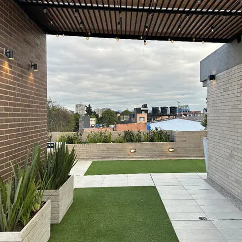 Terraza social de 5924 LOFT terminada, con pérgola, zona verde y jardineras